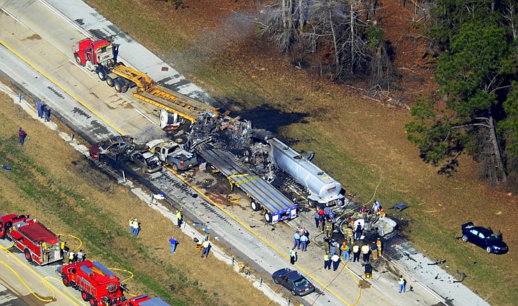 Emergency workers and firemen work the scene of a pileup Wednesday on Interstate 16 near Jeffersonville, Ga. More than two dozen vehicles collided on the foggy Georgia interstate, killing four people and leaving several others hurt, officials said.
