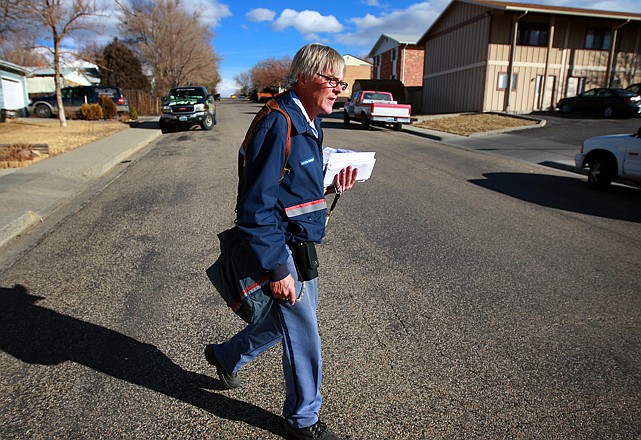Mail carrier Lou Holscher walks his route Wednesday on in Casper, Wyo. The U.S. Postal Service on Wednesday announced plans to cut Saturday mail deliveries to save about $2 billion per year and offset declines in letter delivery. Holscher has worked for the Casper Post Office for almost 30 years and said he has seen the volume of mail drop off significantly in recent years. 