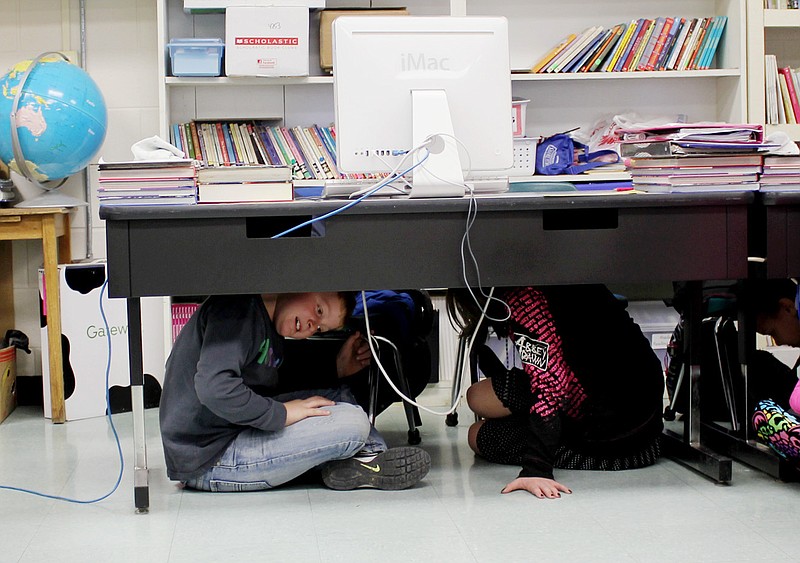 Fourth graders at Bush Elementary School in Fulton huddle under a table during the statewide Great Central U.S. ShakeOut earthquake drill.