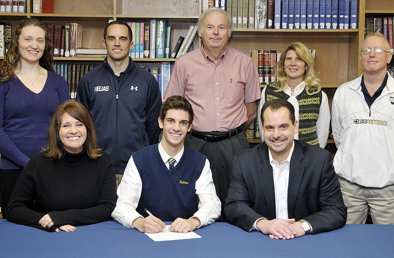 Griffin McCurren of Helias High School (seated, center) signs a letter of intent to run track at St. Louis University. Also seated are Susan and Terry McCurren. Standing (from left) are Helias assistant coach Leslie Verslues, Helias head coach Chip Malmstrom, and Helias assistant coaches Tom Emmel, Margaret Shimkus and Mark Ordway.