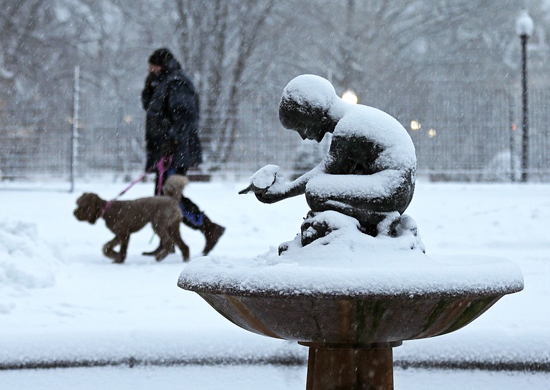 A man walks his dog past the snow covered "Boy and Bird" fountain in the Boston Public Garden in Boston, Friday, Feb. 8, 2013. Mass. Gov. Deval Patrick declared a state of emergency Friday and banned travel on roads as of 4 p.m. as a blizzard that could bring nearly 3 feet of snow to the region began to intensify. As the storm gains strength, it will bring "extremely dangerous conditions" with bands of snow dropping up to 2 to 3 inches per hour at the height of the blizzard, Patrick said. 