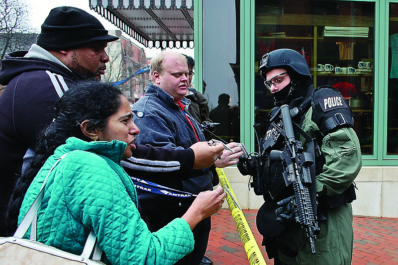 A police officer checks identification of employees outside the New Castle County Courthouse in Wilmington, Del., after three people died Monday morning in a shooting at the courthouse.