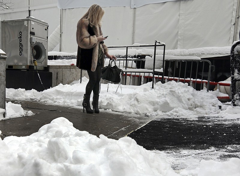 A woman checks her mobile phone Saturday outside Lincoln Center, home of New York's Fashion Week shows. In New York City, the snow total in Central Park was 8.1 inches by 3 a.m.