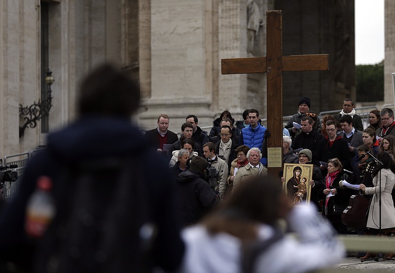 A group of faithful of the Youth Group of San Lorenzo hold a wooden cross Monday in St Peter's Square as they recite their daily rosary, at the Vatican. Pope Benedict XVI said Monday he lacks the strength to fulfill his duties and on Feb. 28 will become the first pontiff in 600 years to resign.