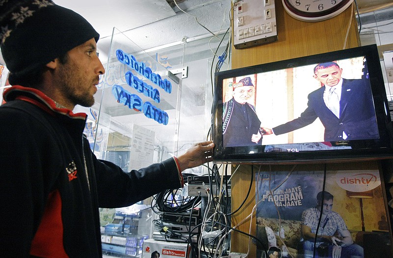 An Afghan man watches U.S. President Barack Obama's State of Union address Tuesday as Obama announced plans to withdraw more troops from Afghanistan and take steps to boost the fragile U.S. economy.