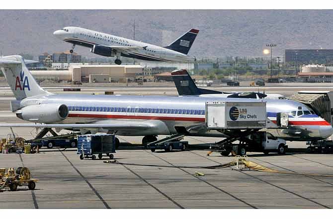 In this June 23, 2008 file photo, a US Airways jet takes off as an American Airlines jet is prepped for takeoff at Sky Harbor International Airport in Phoenix. The merger of US Airways and American Airlines has given birth to a mega airline with more passengers than any other in the world.