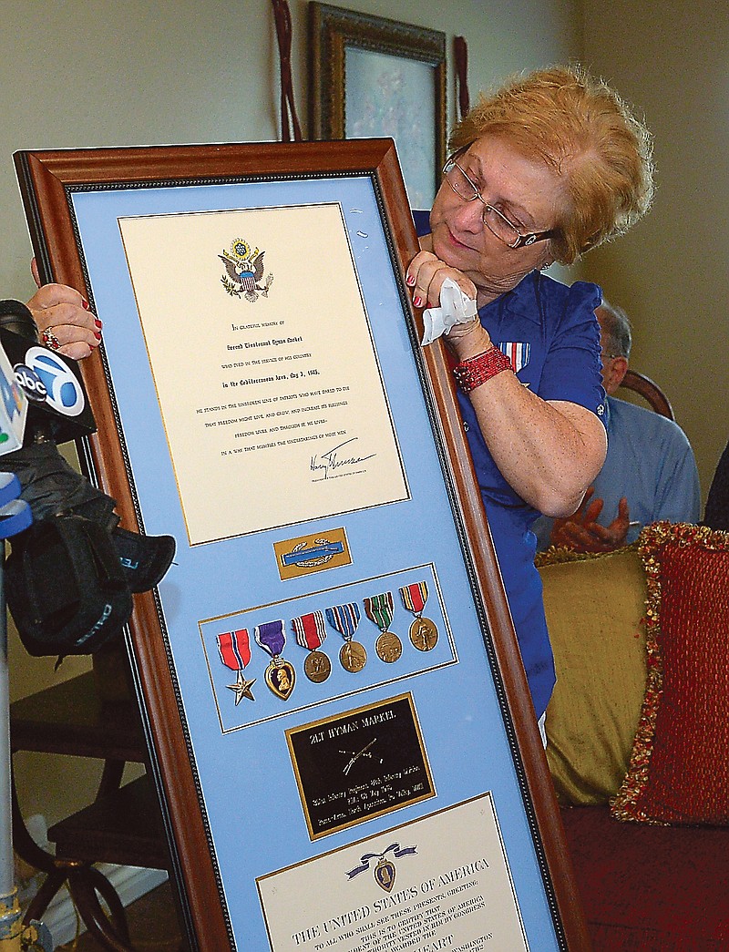 Hyla Merin holds a plaque that contains medals, from left, the Bronze Star, the Purple Heart, the Army Good Conduct Medal, American Campaign Medal, European-African-Middle Eastern Campaign Medal and the World War II Victory Medal along with a Silver Star that was pinned to her  during a ceremony Sunday. The medals were presented posthumously to her father after being recently discovered in an apartment where Merin's mother and aunts had once lived.