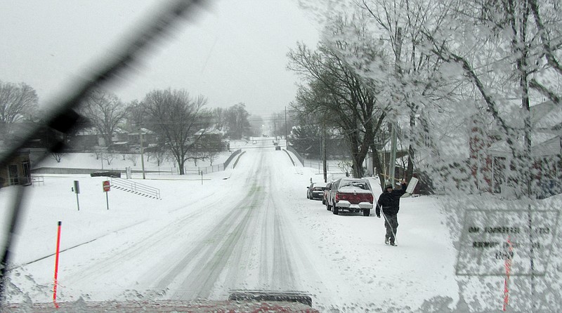 A city resident waves as a Jefferson City snow plow works to clear the roads during a winter storm.