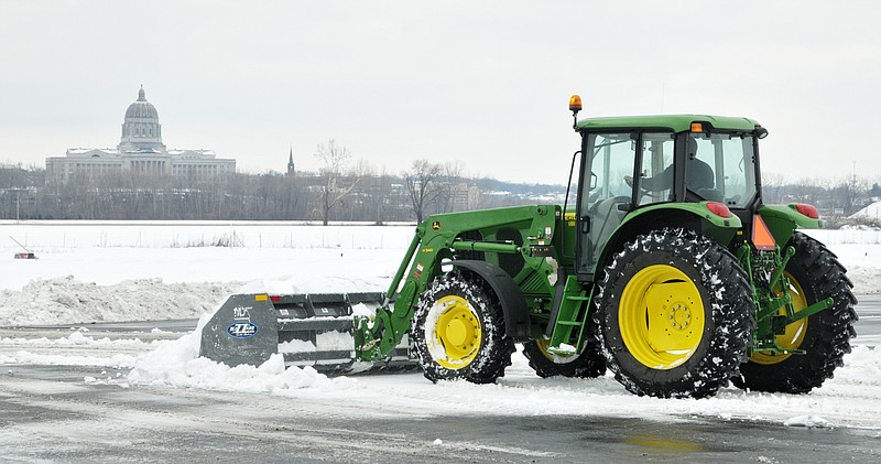 Drew Leary, a part-time employee at Jefferson City Memorial Airport, operates a tractor Friday with a Blizzard Buster scoop. He and two other airport crew members were responsible for cleaning the tarmac, crossovers and runways. They did have a couple of takeoffs and landings Friday but traffic count overall was down because of the weather.