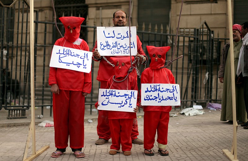 An Egyptian man with his three children wear red Friday during a symbolic hanging at an anti-government protest in front of Egypt's high court building in downtown Cairo. The Arabic writing on the banners reads, "death is more honorable for me and my children than poverty and hunger," and "Jeeka, Christy and Mohammed to heaven."