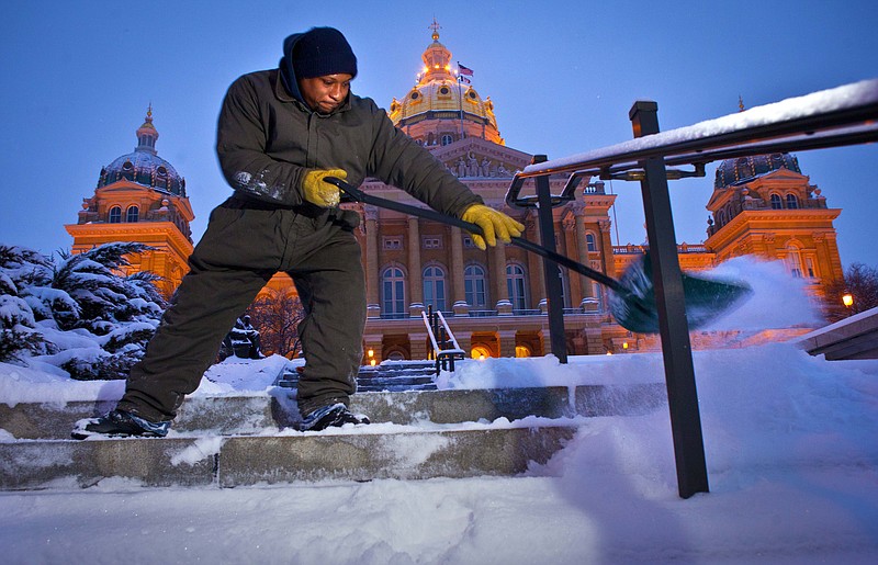 Billie Byrd, of Des Moines, clears the steps of the Iowa Capitol on Friday, after an overnight snowstorm dumped six inches in Des Moines. The snowstorm left behind varying amounts of snow and ice across the Midwest, causing difficult travel conditions. Powerful wind gusts created large snow drifts on many roadways, making navigating the slick conditions a challenge.