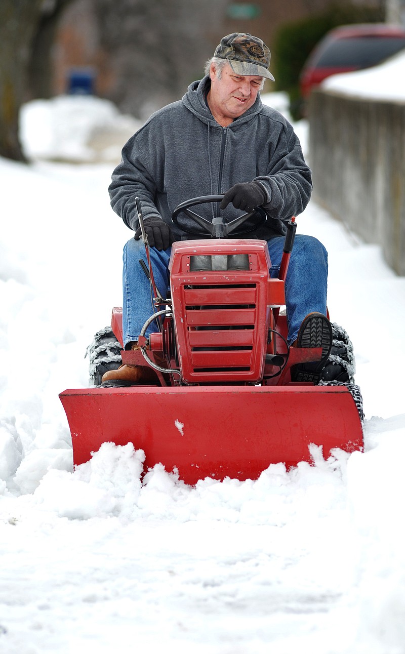 Don Kliethermes of Missouri River Regional Library uses a riding mower with a 36-inch blade to plow snow from the sidewalk around the library's property. He was trying to clear the way for the expected winter precipitation so the snow buildup was managable.