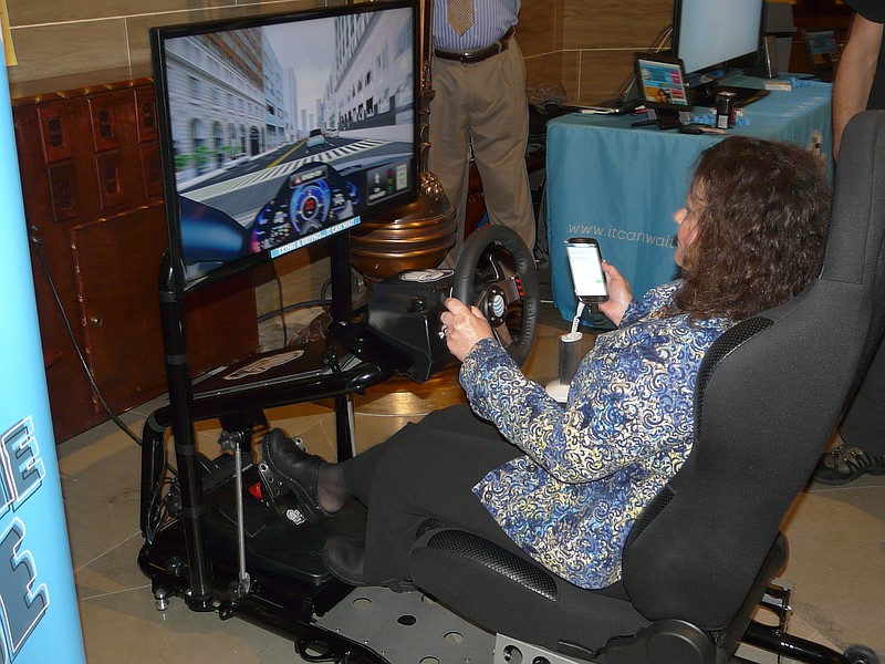 State Rep. Donna Lichtenegger, R-Jackson, attempts to read and send text messages on a cell phone while driving, using a simulator provided by AT&T, Tuesday morning at the Capitol.