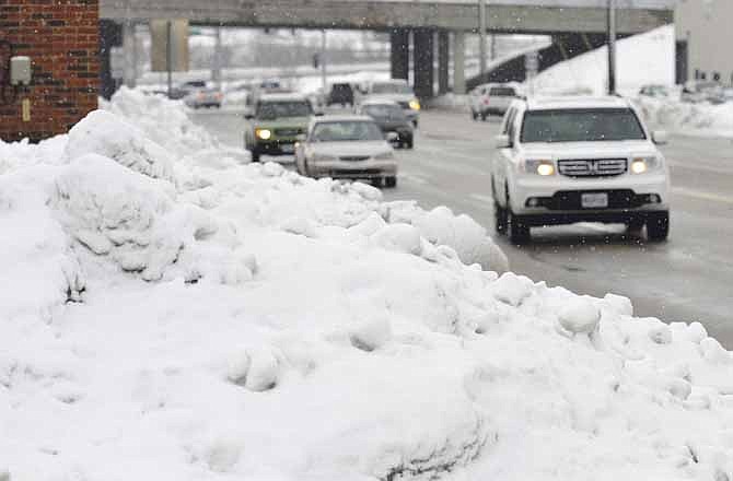 Motorists along Missouri Boulevard drive past mounded snow all along the Jefferson City thoroughfare. With a couple of snowfalls and not much melting time, snow is piling up around mid-Missouri.