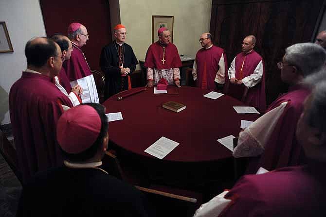 Cardinal Tarcisio Bertone, Vatican Secretary of State, at center left with red skull cap, officially takes over the vacant see as camerlengo, chamberlain, before sealing Pope Benedict XVI's apartment, after Benedict left the Vatican, Thursday, Feb. 28.