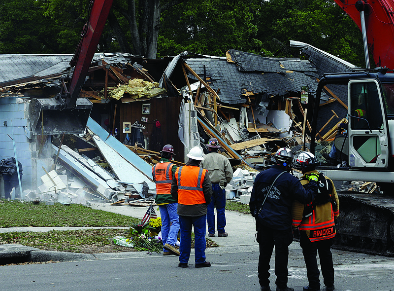 Demolition experts watch as the home of Jeff Bush, 37, is destroyed Sunday after a sinkhole opened up underneath it late Thursday evening in Seffner, Fla.