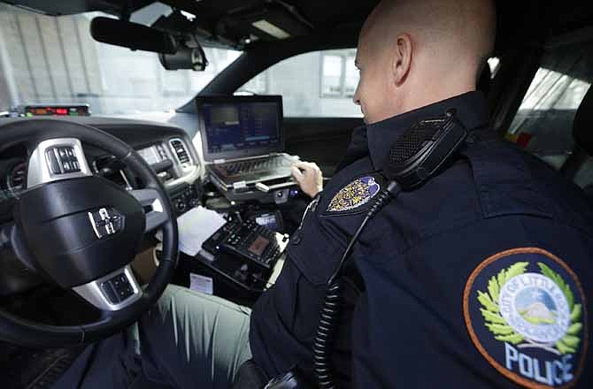 In this photo taken Jan. 16, 2013, Little Rock Police Officer Grant Humphries loos at a computer monitor connected to a camera mounted near the rear window of his patrol car in Little Rock, Ark. The device is part of a system that scans traffic on the streets, relaying the data it collects to the computer for sifting. Police say the surveillance helps identify stolen cars and drivers with outstanding arrest warrants.