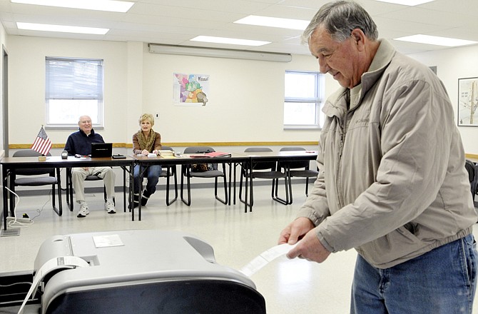 ABOVE: When he voted about 12:30 p.m. Tuesday, Jerry Sanning was the 45th person to cast a ballot at the polling place located inside Missouri Electric Co-op. That location was for residents of Ward 1/Precinct 4. In the background, election officials Ron Cauwenbergh and Evelyn Motte look on as Sanning inserts his ballot into the machine. 
