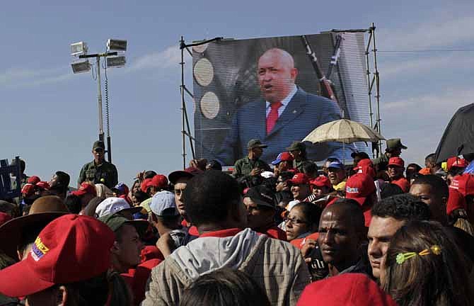 A screen showing a video image of Venezuela's President Hugo Chavez plays Friday in front of the site where Chavez's funeral ceremony took place as people gather outside the military academy in Caracas, Venezuela. Chavez died on Tuesday after a nearly two-year bout with cancer. He was 58.