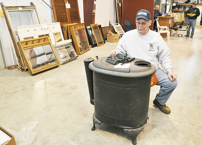 Preston Hunter, one of several volunteers at the River City Habitat for Humanity ReStore prepares to reattach a leg onto the wood stove before him. Typically this area is filled with kitchen and bathroom cabinetry, but is currently empty.