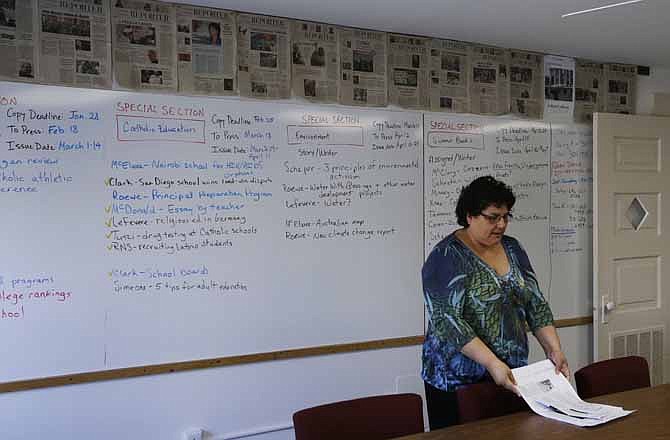 In this Wednesday, March 6, 2013 photo, editor Toni Ortiz works in a conference room at the National Catholic Reporter in Kansas City, Mo. The National Catholic Reporter, a newspaper known for unflinching coverage of the Catholic church scandal, was rebuked by a bishop in its own backyard after calling for his ouster in a battle that illustrates tensions between U.S. bishops and groups that call themselves Catholic but aren't sanctioned by the church. 