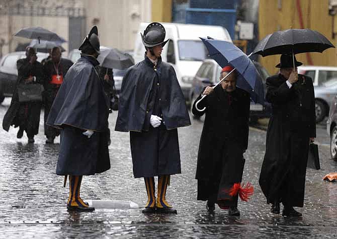 Cardinal Carlo Caffarra, second from right, and Cardinal Raymond Leo Burke, right, walk past two Swiss guards Friday as they leave after a meeting at the Vatican. The Vatican says the conclave to elect a new pope will start Tuesday.