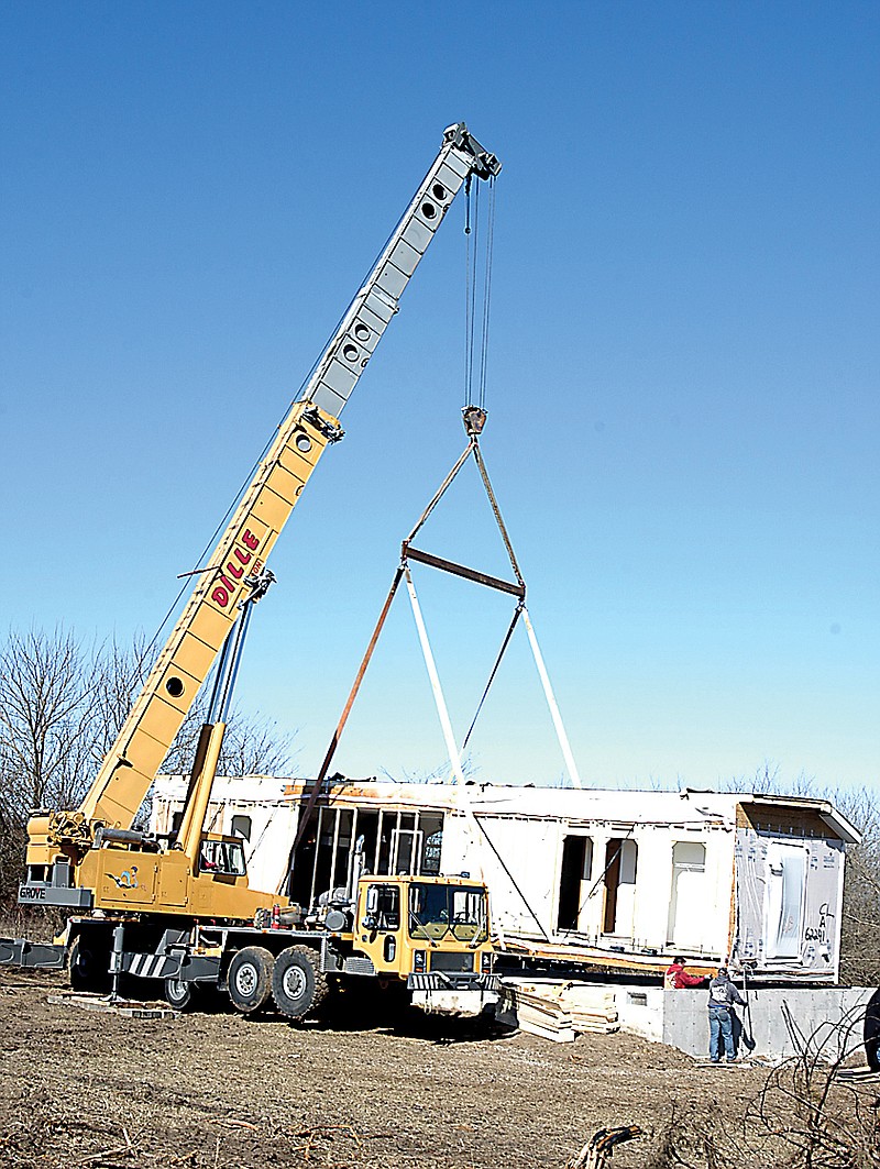 A crane sets half of Dee Irey's new modular home on its foundation at a location near Latham. 
