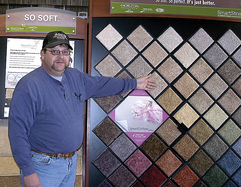 Darryl Dutcher of K.A. Dutcher Paint and Carpet, points out samples of the new fiber product carpeting, called Smartstrand, which are more durable and cleanable than older carpeting. Dutcher recommends professional steam cleaning to remove the winter dirt and grit.