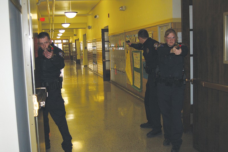 Armed with airsoft guns, John Williams, Brandi Blankenship and Anthony Bell practice taking position in a Fulton Middle School during active shooter training the Fulton Police Department held there Wednesday. The police department and Fulton Public Schools are increasing the bredth of their preparedness training for a school shooter incident to include the middle and elementary schools following the Sandy Hook shooting.