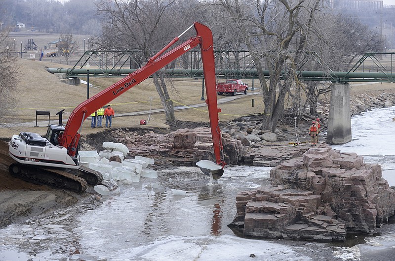 An excavator is used to break up a sheet of ice Friday on the Big Sioux River, below the falls at Falls Park, while crews work to recover the bodies of two adults who went into the water to rescue a 6-year-old boy who fell into the water Thursday evening in Sioux Falls, S.D.