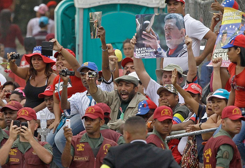 People react Friday as the coffin containing the remains of Venezuela's late President Hugo Chavez is driven past in a procession from the military academy to the military museum, in Caracas, Venezuela. Chavez's body is being transferred Friday from the military academy where it has been lying in state to the military museum that will serve as final resting place. 