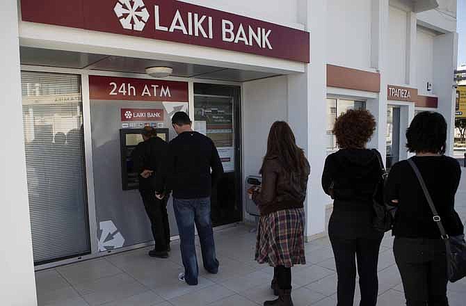 People queue to use an ATM machine outside of a Laiki Bank branch in Larnaca, Cyprus, Saturday, March 16, 2013. Many rushed to cooperative banks which are open Saturdays in Cyprus after learning that the terms of a bailout deal that the cash-strapped country hammered out with international lenders includes a one-time levy on bank deposits. The move, decided in an extraordinary meeting of the finance ministers of the 17-nation eurozone in the early hours Saturday, is a major departure from established policies. Analysts have warned that making depositors take a hit threatens to undermine investors' confidence in other weaker eurozone economies and might possibly lead to bank runs. 