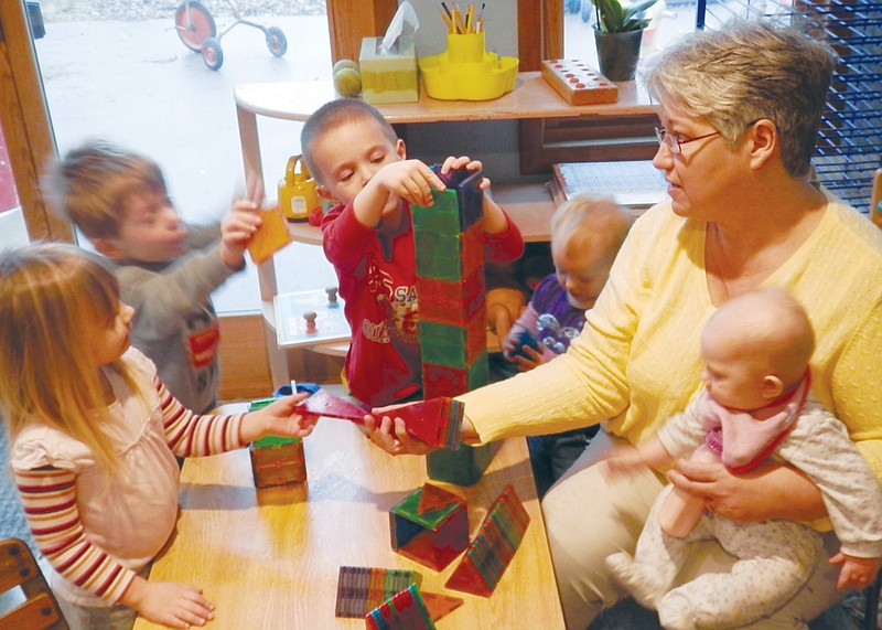 Kocher Child Care owner Meg Kocher helps some of her preschoolers build their brains by building a tower. Kocher recently received a $1,000 grant from the Terri Lynne Lokoff Child Care Foundation to encorporate "The Science Squad:" a program to encourage children to explore their world around them and foster a lasting love of science.