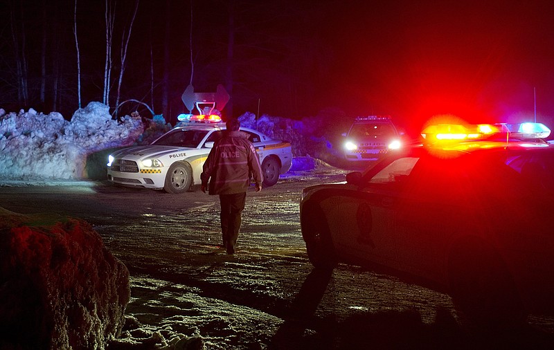 Police vehicles block a road Sunday just outside the town of Chertsey, Quebec, during a search for escaped prisoners. A dramatic daylight jailbreak involving two Quebec inmates climbing a rope into a hovering helicopter swiftly escalated into a large police operation Sunday night. 