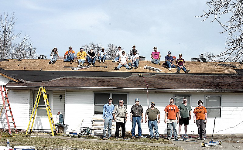 The crew of adults and youth learning construction in preparation for a summer mission trip are at work on the roof of this house near the Missouri River.
Rev. Brian Bish, standing, takes an active part in the task of reroofing a house belonging to a man in need of assistance. 