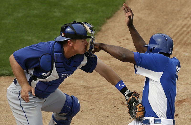 Dodgers catcher Tim Federowicz gets a fist to the mask as he tags out Lorenzo Cain of the Royals at home during the sixth inning of Wednesday's game in Surprise, Ariz.