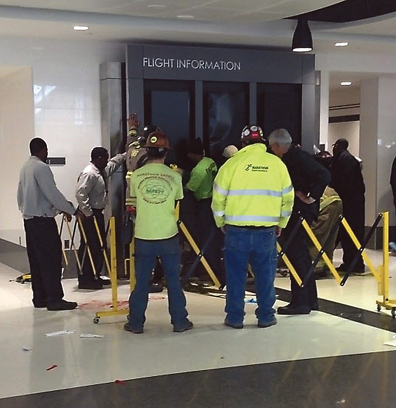 People hold up a message board sign that fell on a family killing a child and injuring the mother and two other children in the terminal at the Birmingham-Shuttlesworth International Airport.