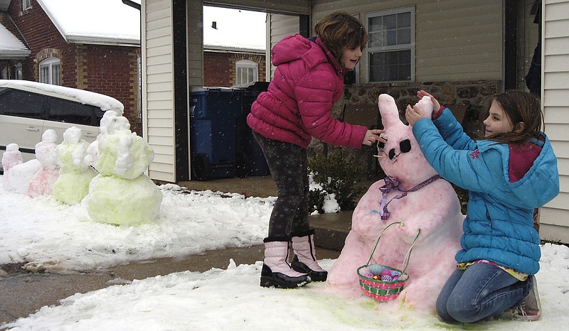 From left, sisters Allison and Madison Meister, 6 and 10, put the finishing touches on their snow Easter bunny, one of several snow Easter creations they made with the help of their mom, Ashley, on Sunday afternoon. 
