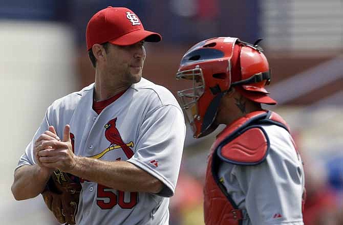 Cardinals starter Adam Wainwright talks with catcher Yadier Molina during Tuesday's game against the Mets in Port St. Lucie, Fla.
