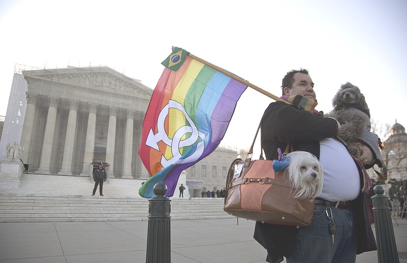 Marcos German Domingues of Massachusetts stands with his dogs Sophia, left, and Georg, right, in front of the Supreme Court in Washington on Wednesday. The Supreme Court, in the second of back-to-back gay marriage cases, turned Wednesday to a constitutional challenge to the federal law that prevents legally married gay Americans from collecting federal benefits generally available to straight married couples.