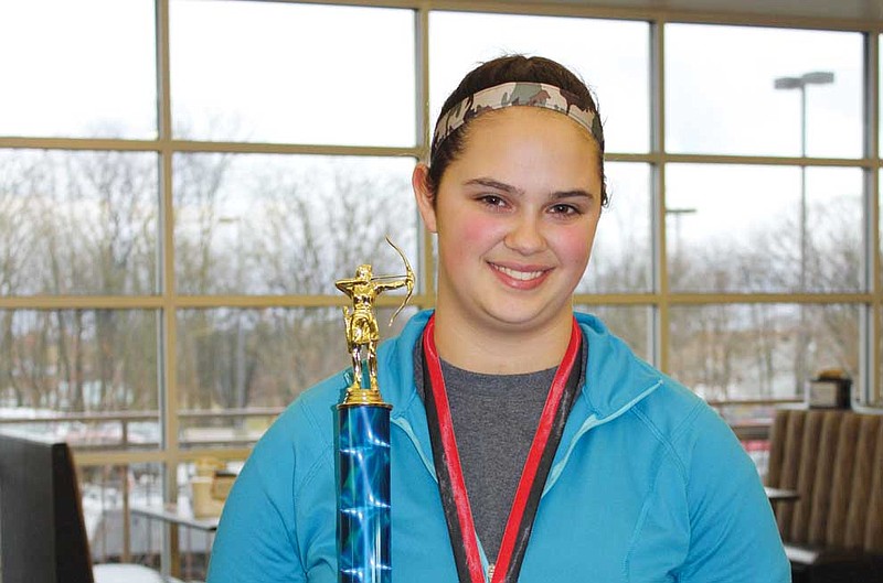Anna Threatt of Fulton poses with her first-place trophy she earned while breaking state records in the Young Adult Female Freestyle Recurve class of the Missouri Bow Hunters Association's State Indoor Championship. Threatt represented the Callaway County 4-H Shooting Sports program, for which she has been practicing archery for three years.