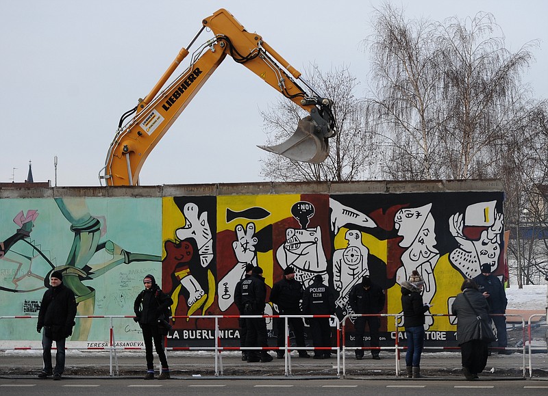 Police officers guard a construction site and sections of the East Side Gallery, while parts of the former Berlin Wall are removed in Berlin, Germany, Wednesday. Work crews backed by about 250 police have removed portions of the Berlin Wall known as the East Side Gallery to make way for an upscale building project, despite demands by protesters that the site be preserved. Plans to remove part of the 3â„4-mile stretch of wall sparked protests that developers were sacrificing history for profit. 