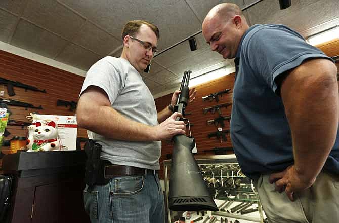 Black Weapons Armory store owner Tommy Rompel, left, shows former mayoral candidate Shaun McClusky, a shotgun at the Tucson, Ariz. store on Thursday, March 28, 2013. The weapon is similar to those to be given away as part of a privately funded program he is launching to provide residents in crime-prone areas with free shotguns so they can defend themselves against criminals.