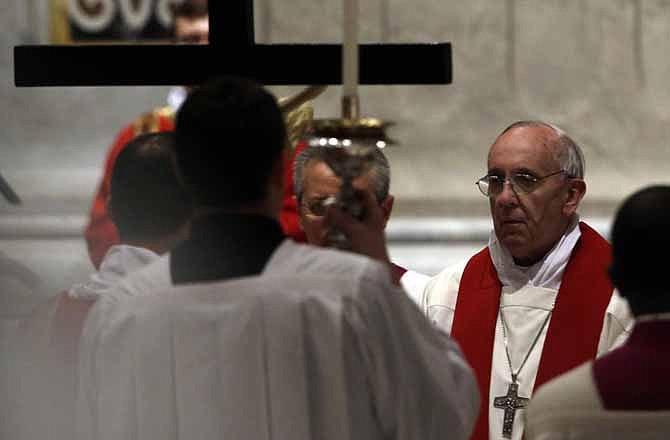 Pope Francis, right, looks up to the Crucifix during the Passion of Christ Mass on Friday inside St. Peter's Basilica, at the Vatican. The new pope began a debate when he violated church law and tradition by including two girls in the ceremonial washing of feet in a Holy Thursday ritual.