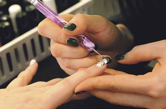 Kim Khue Nguyen delicately paints Asian-inspired designs on a customer's newly manicured nails recently at Kim's Nail Salon in Jefferson City.