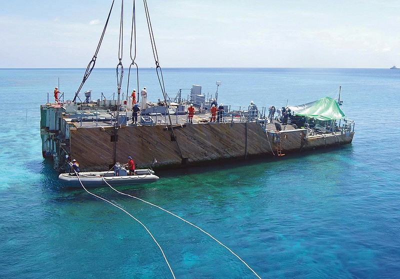 Workers prepare for lifting of a part of the dismantled hull of the USS Guardian on the Tubbataha Reef, a World Heritage Site in southwest of the Philippines. 