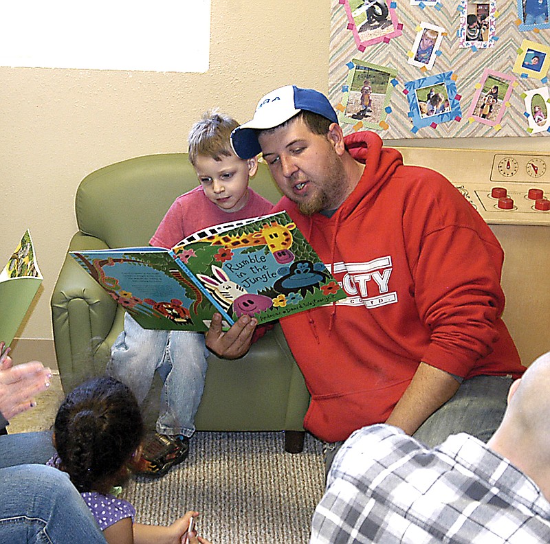 At the "100 man lunch" event at California Head Start, Rob DeCosta reads to his son before the meal of pulled pork sandwiches and several side dishes.