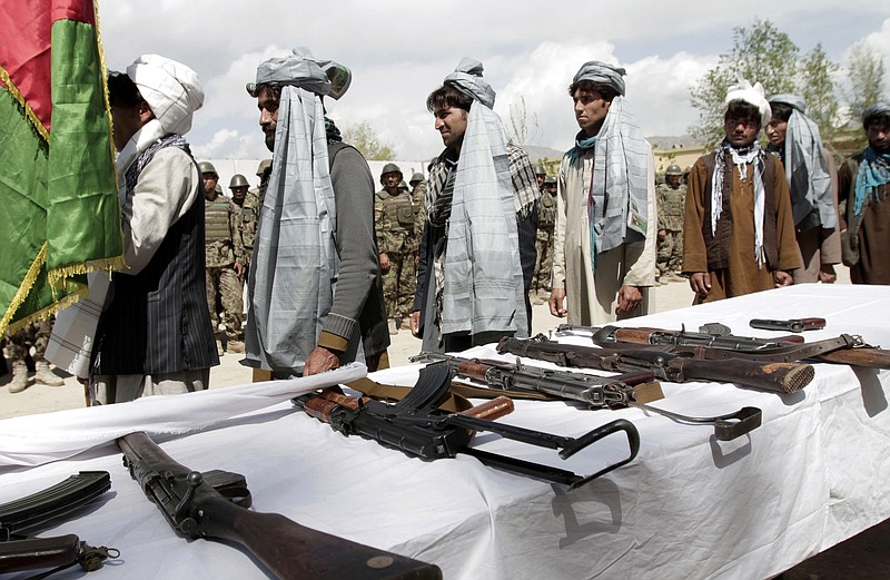 Former Taliban line up Wednesday after turning in their weapons during a ceremony with the Afghan government in Mehterlam, Laghman province, east of Kabul, Afghanistan.