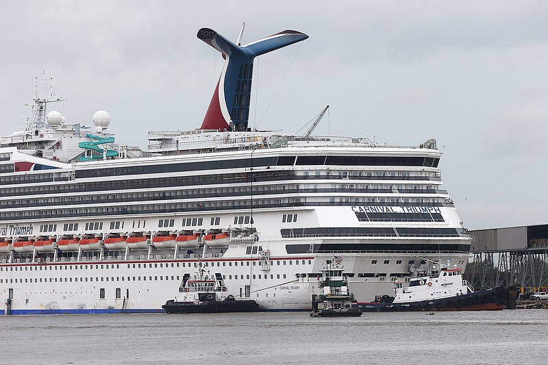 Tug boats maneuver around the Carnival cruise ship Triumph as she rests against a dock on the east side of the Mobile River after becoming dislodged from its mooring at BAE Shipyard during high winds Wednesday in Mobile, Ala. 