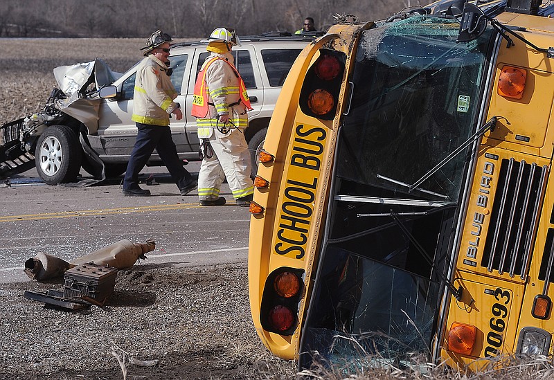 Emergency personnel walk the scene where a school bus carrying 34 elementary school children overturned Friday near Wadsworth, Ill. Authorities say one person has died and more than three dozen people are injured.
